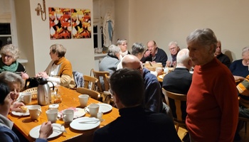 Blick auf den gut gefüllten Pfarrraum. Viele Menschen sitzen an den Tischen, frühstücken und unterhalten sich angeregt.